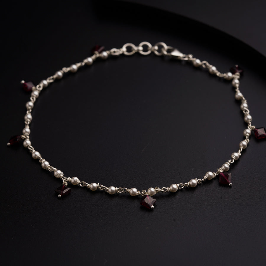 a bracelet with pearls and garnets on a black surface
