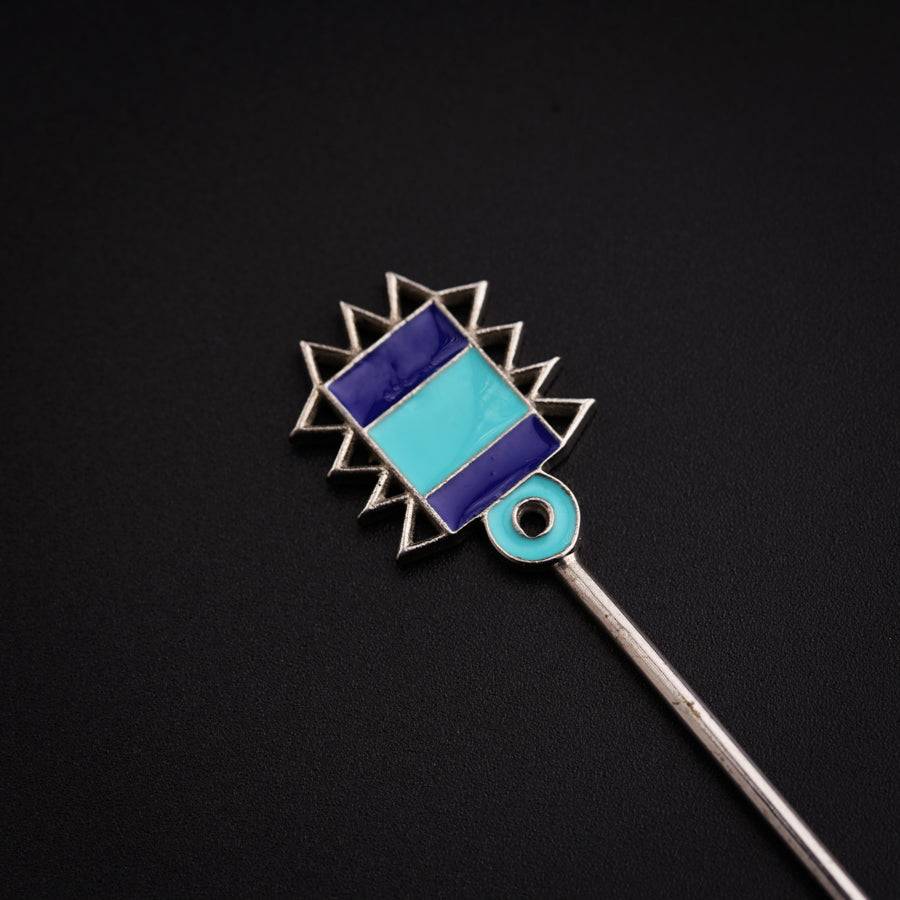 a blue and silver brooch sitting on top of a black surface