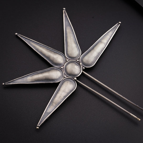 a metal object on a black surface with a clock in the background