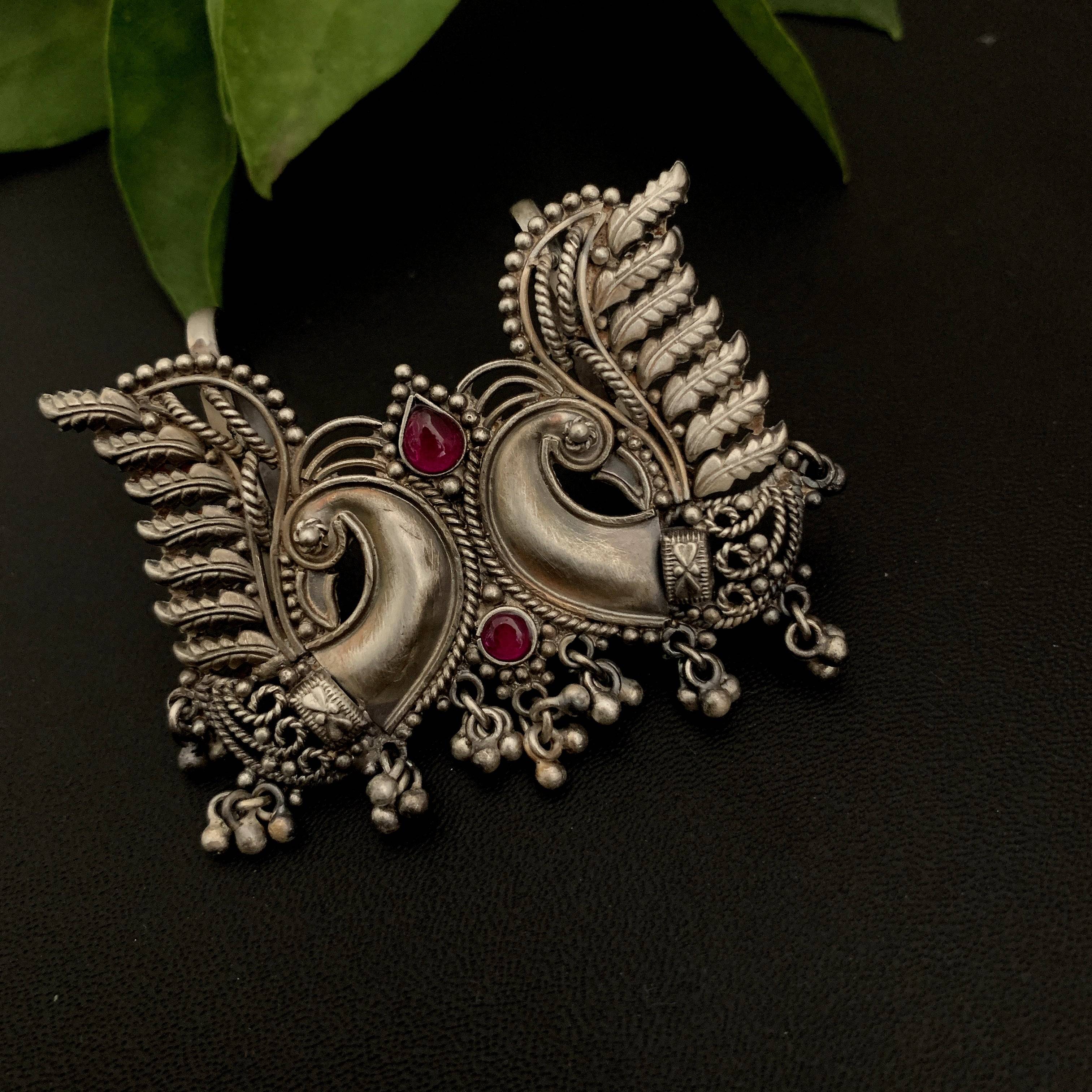 a close up of a brooch with a plant in the background