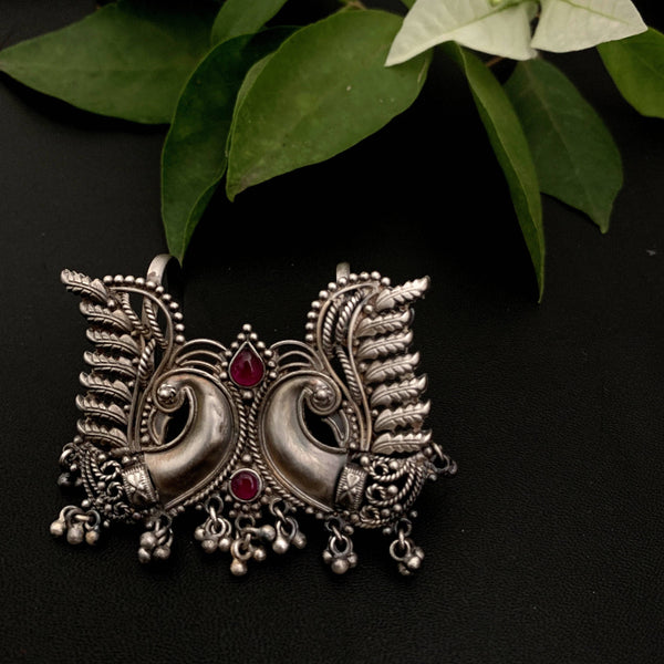 a close up of a brooch with a plant in the background