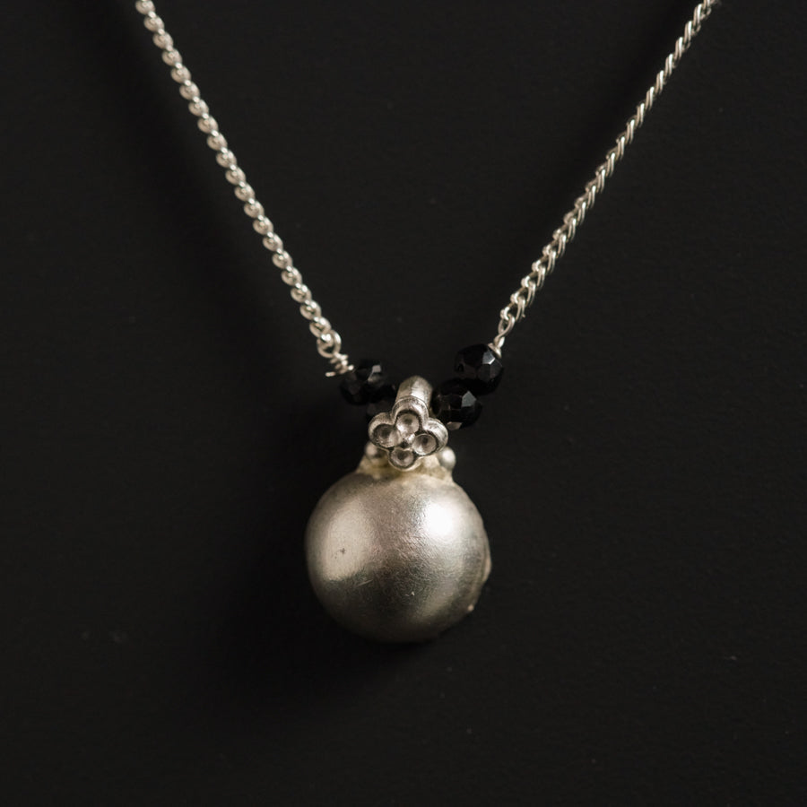 a necklace with a silver ball and a skull on it