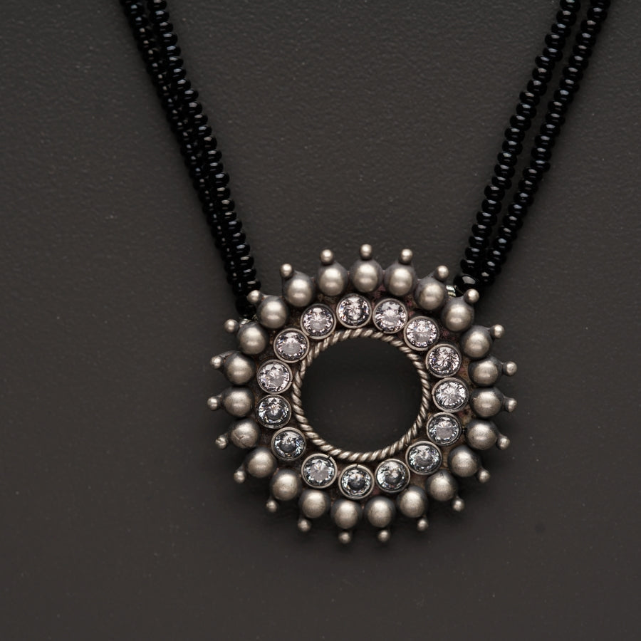 a black beaded necklace with a silver circle