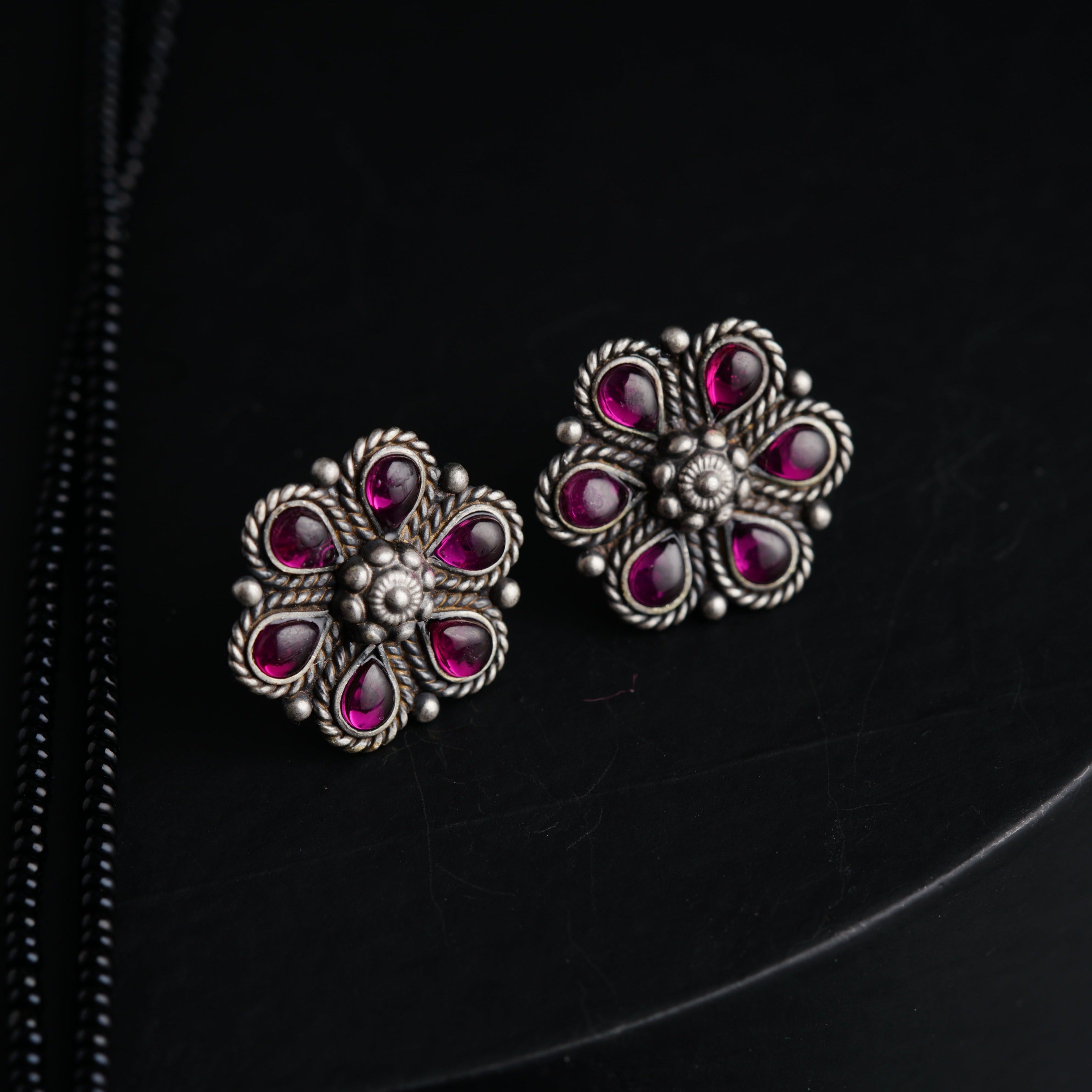 a pair of pink and silver earrings on a black surface