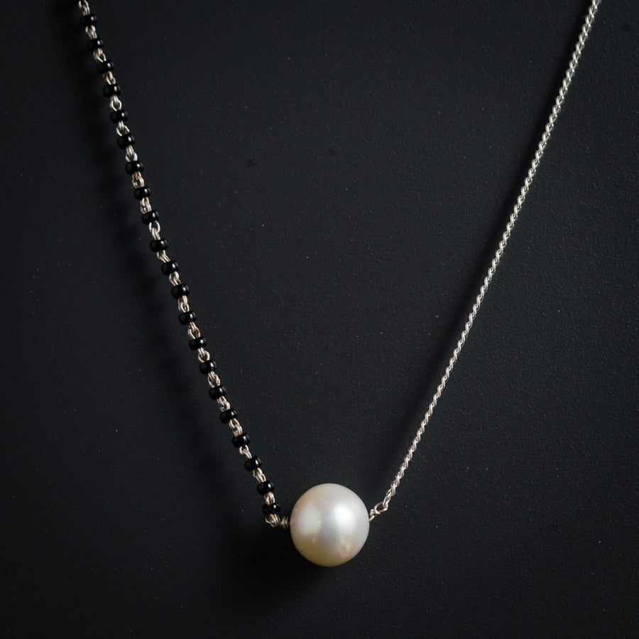 a necklace with a white pearl hanging from it