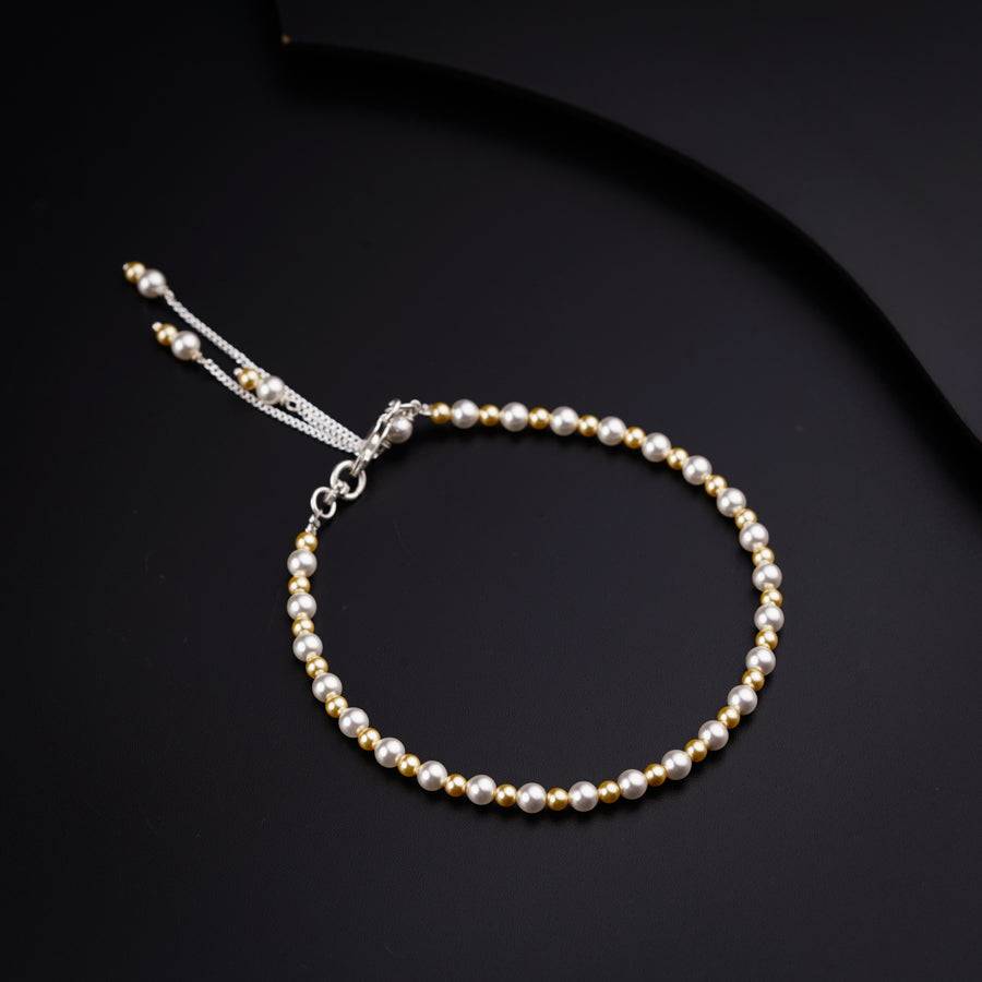 a bracelet with pearls on a black background