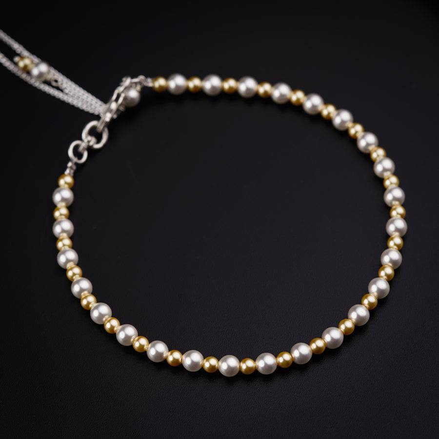 a white and gold beaded bracelet on a black surface