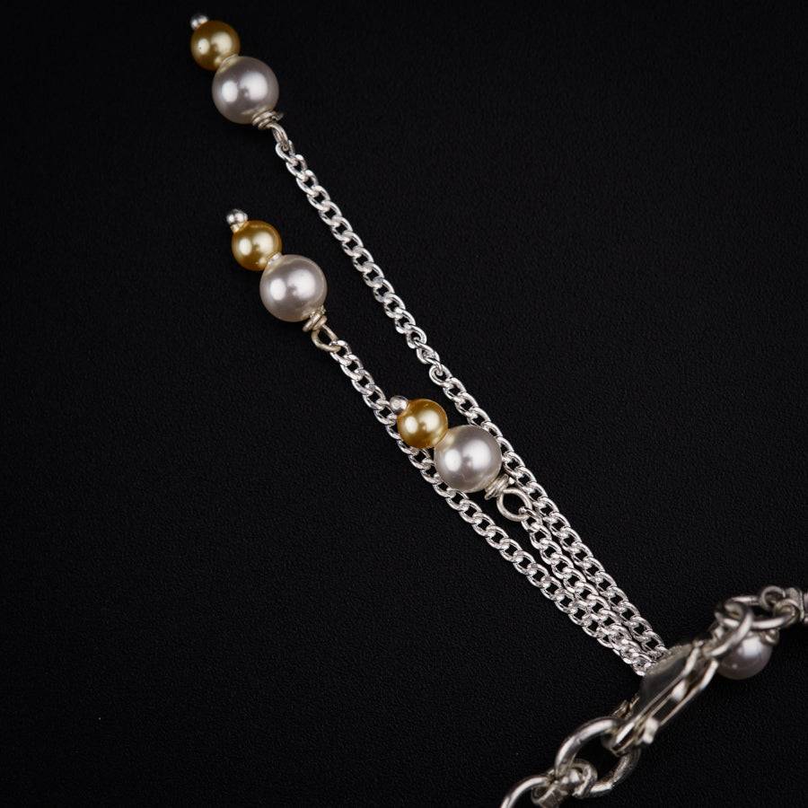 a necklace with pearls and chains on a black background