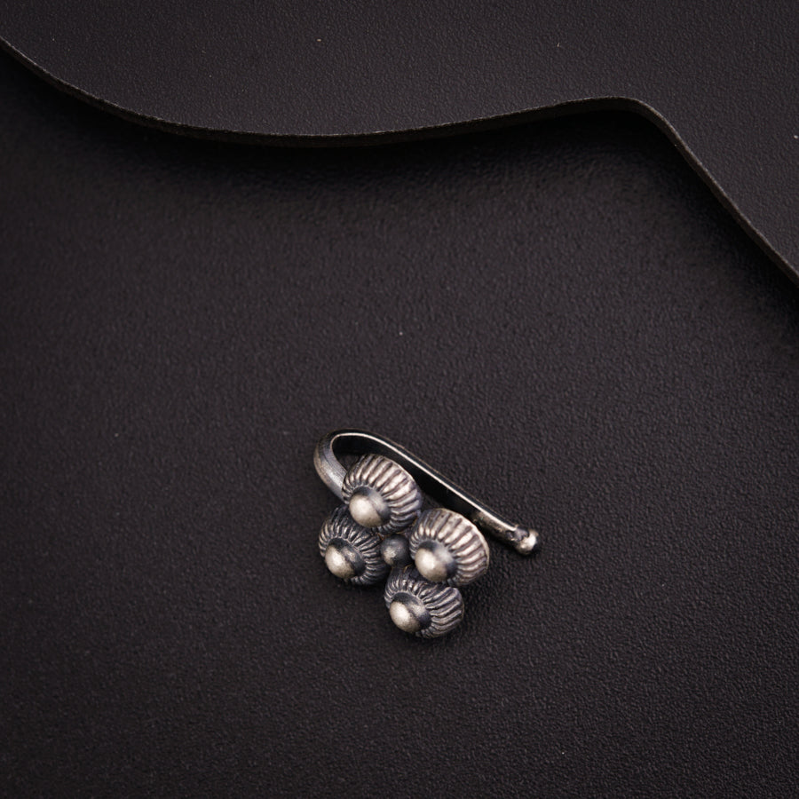 a silver brooch sitting on top of a black surface