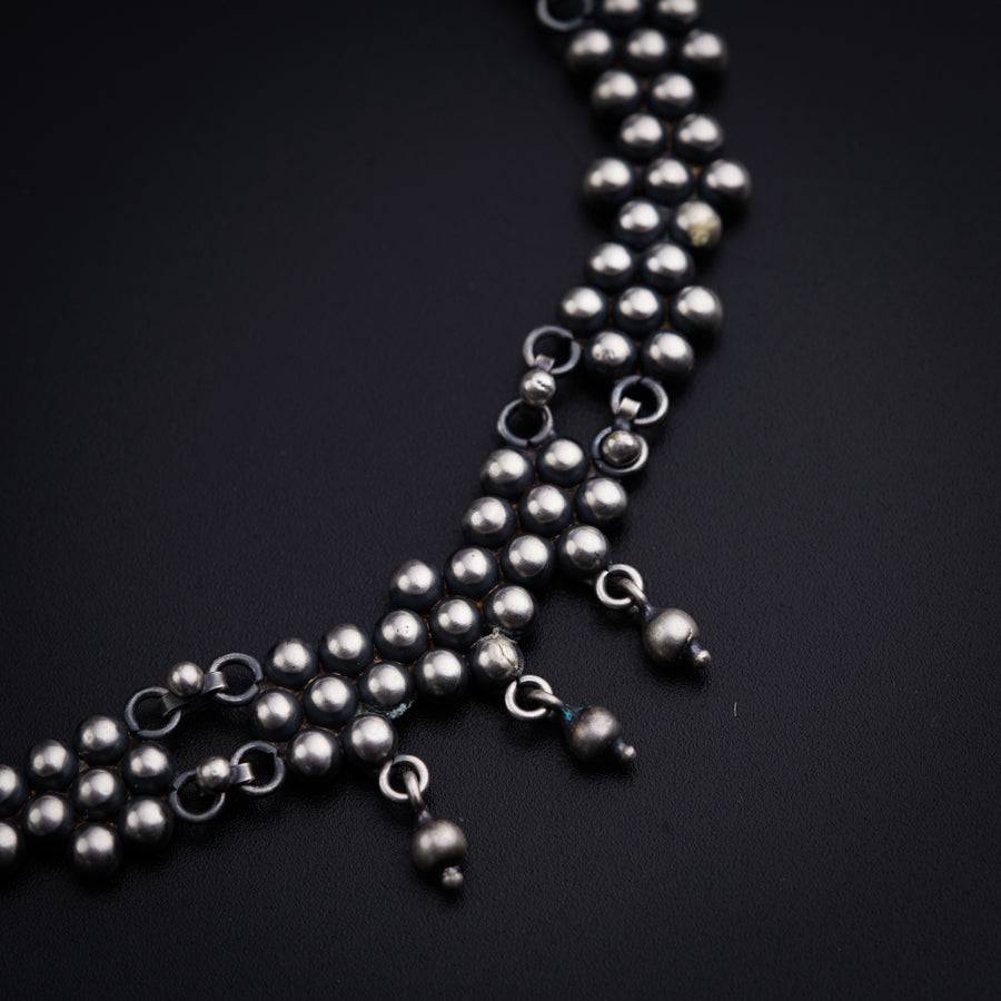 a long strand of silver beads on a black surface