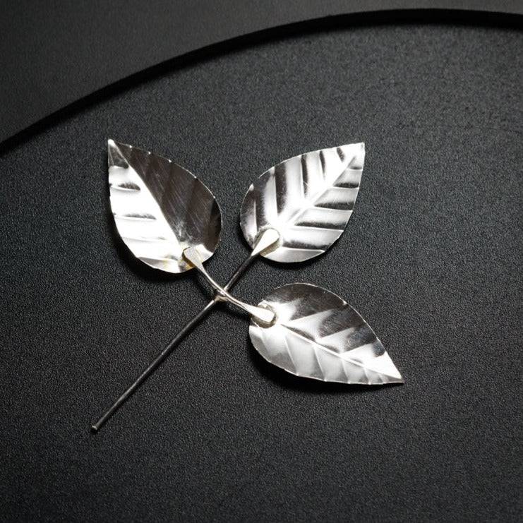 a pair of silver leaves sitting on top of a table