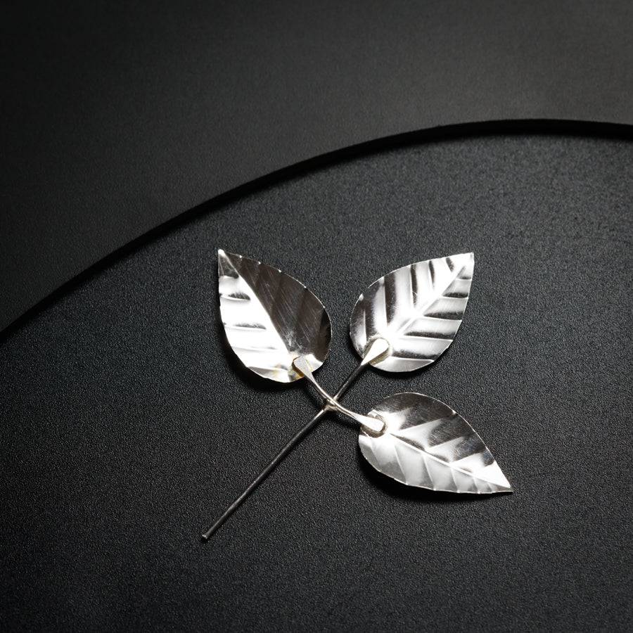 a silver brooch with two leaves on it