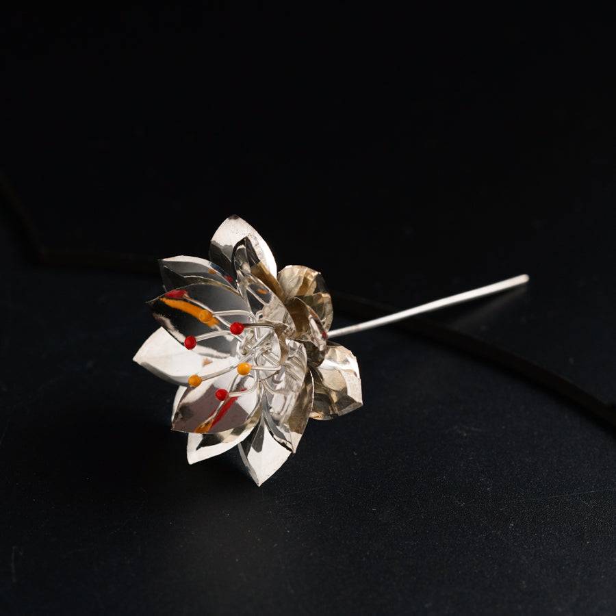 a brooch with a flower on a black surface