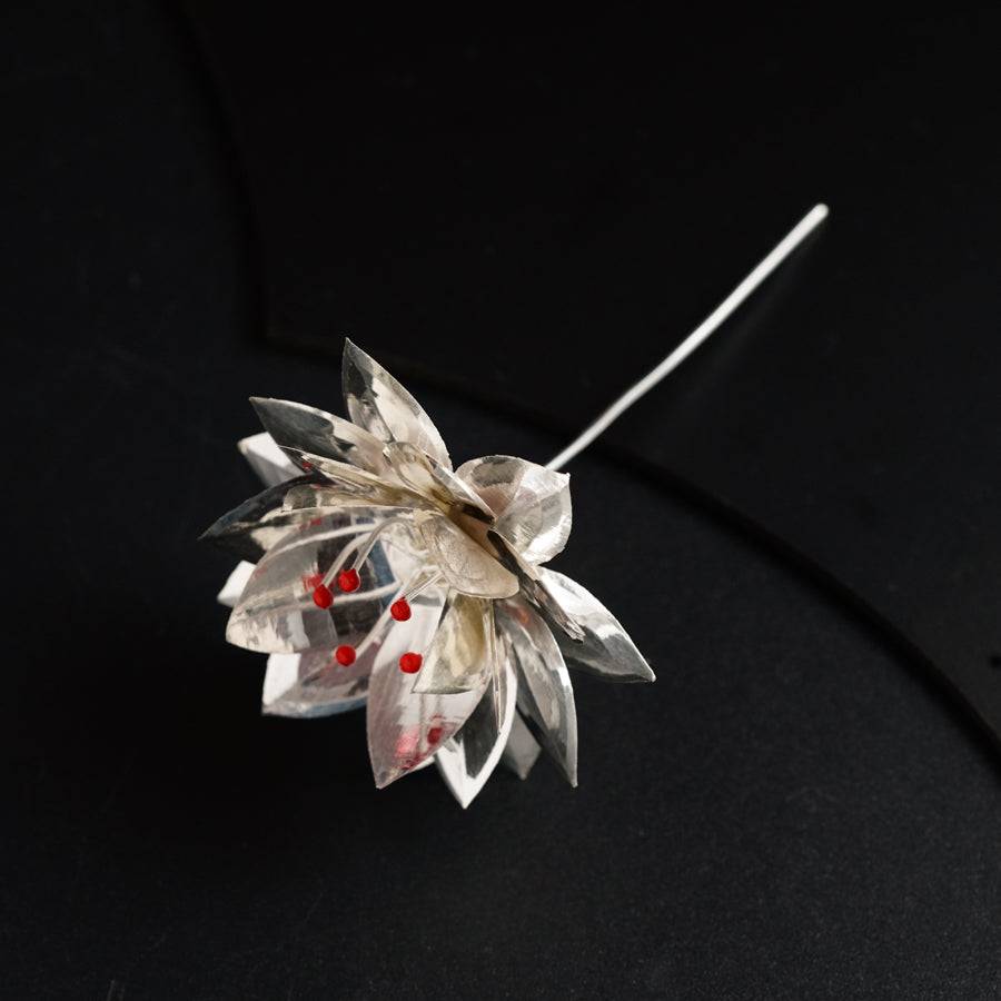 a silver brooch with red beads on a black surface