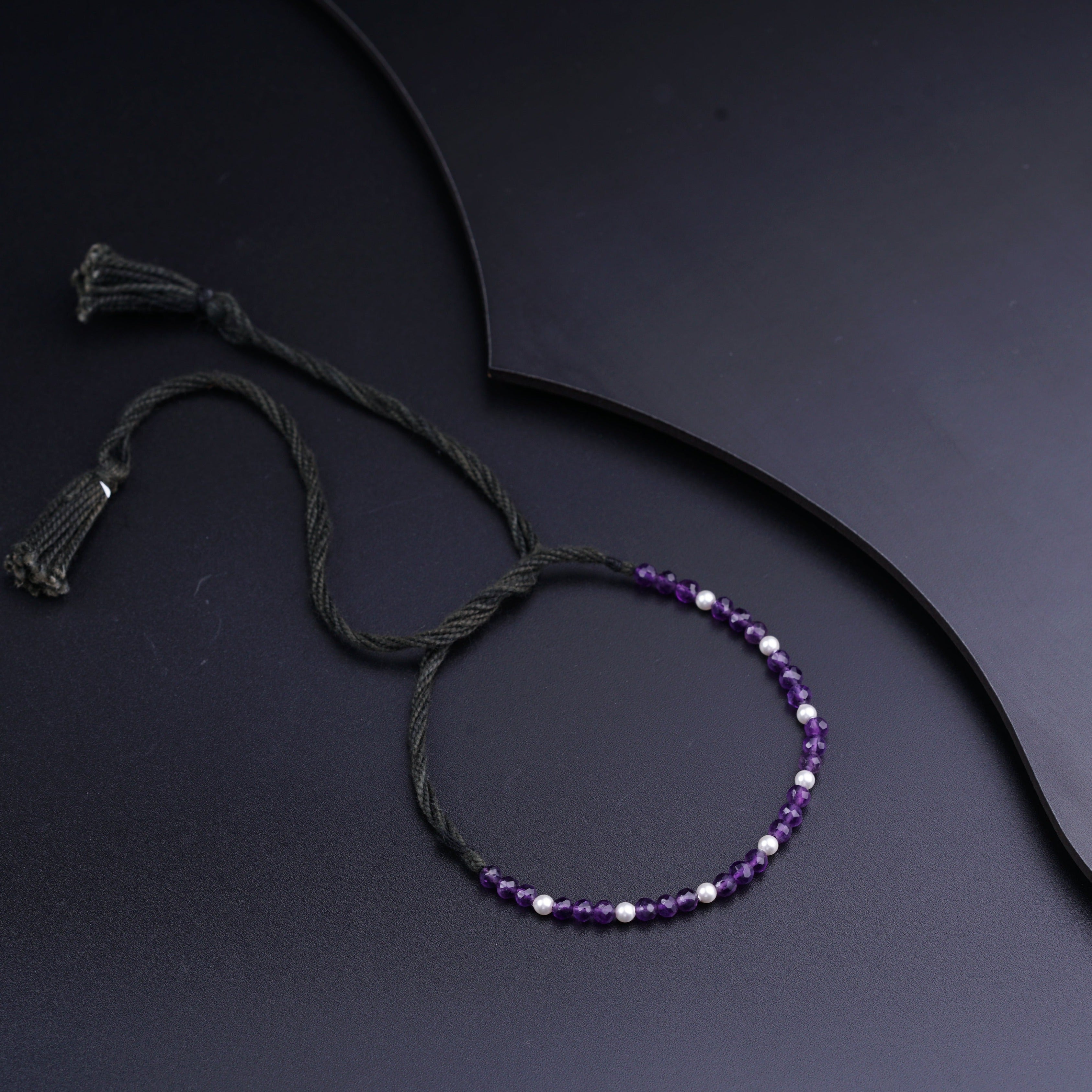 a purple beaded bracelet with a tassel