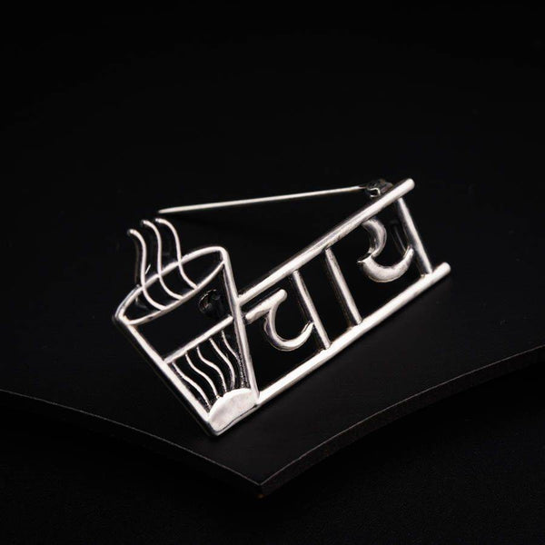 a silver brooch with a cup of coffee on it