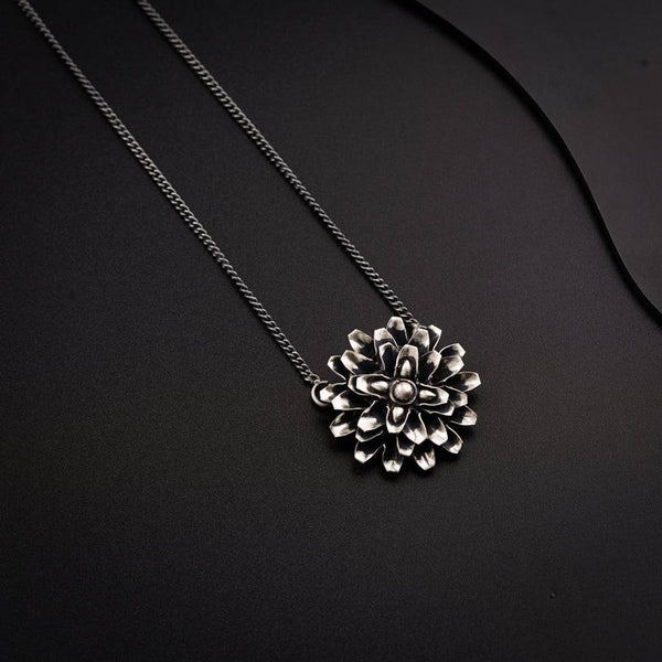 a necklace with a flower on a black background