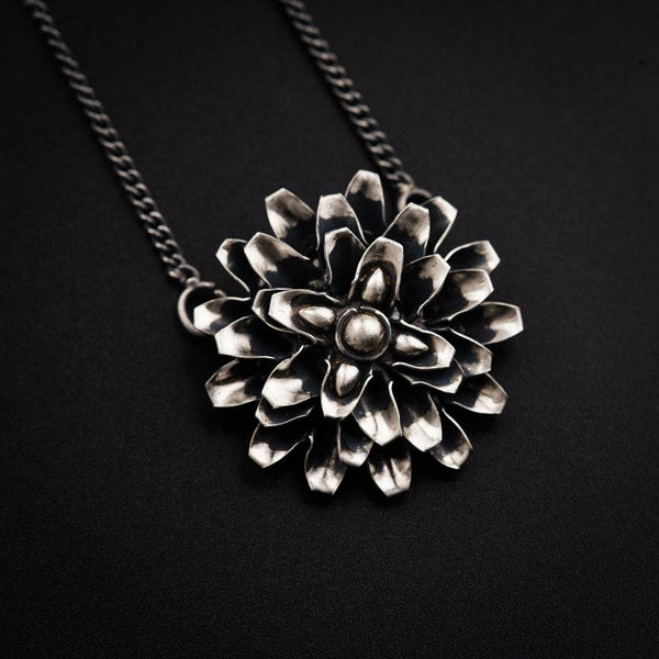 a silver flower necklace on a black background