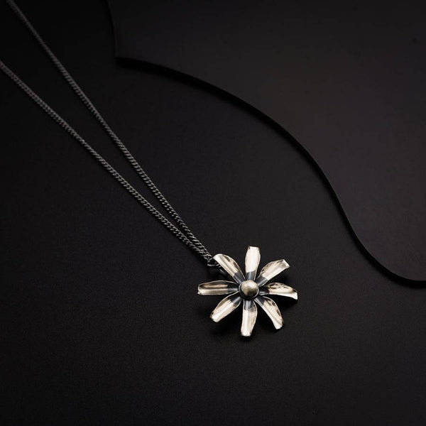 a silver necklace with a flower on a black background