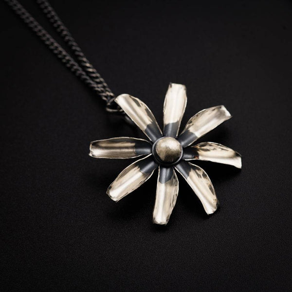 a silver and black flower pendant on a chain