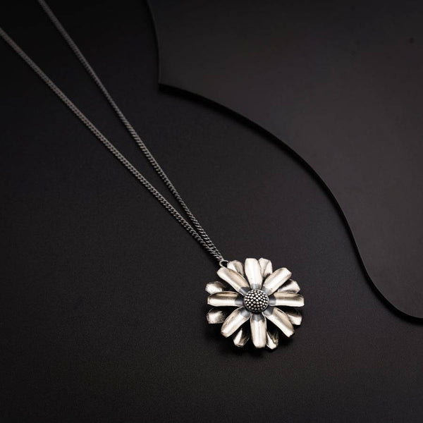 a necklace with a flower on a black background