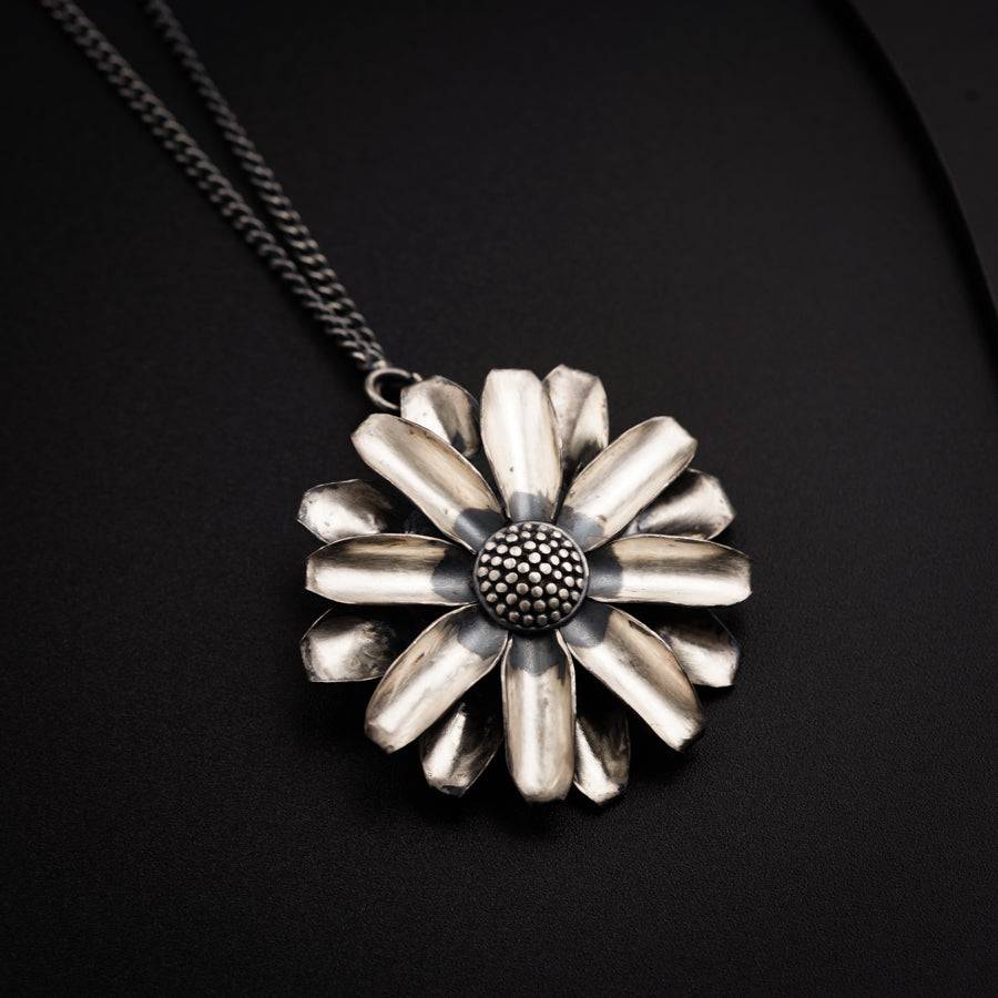a silver flower necklace on a black background