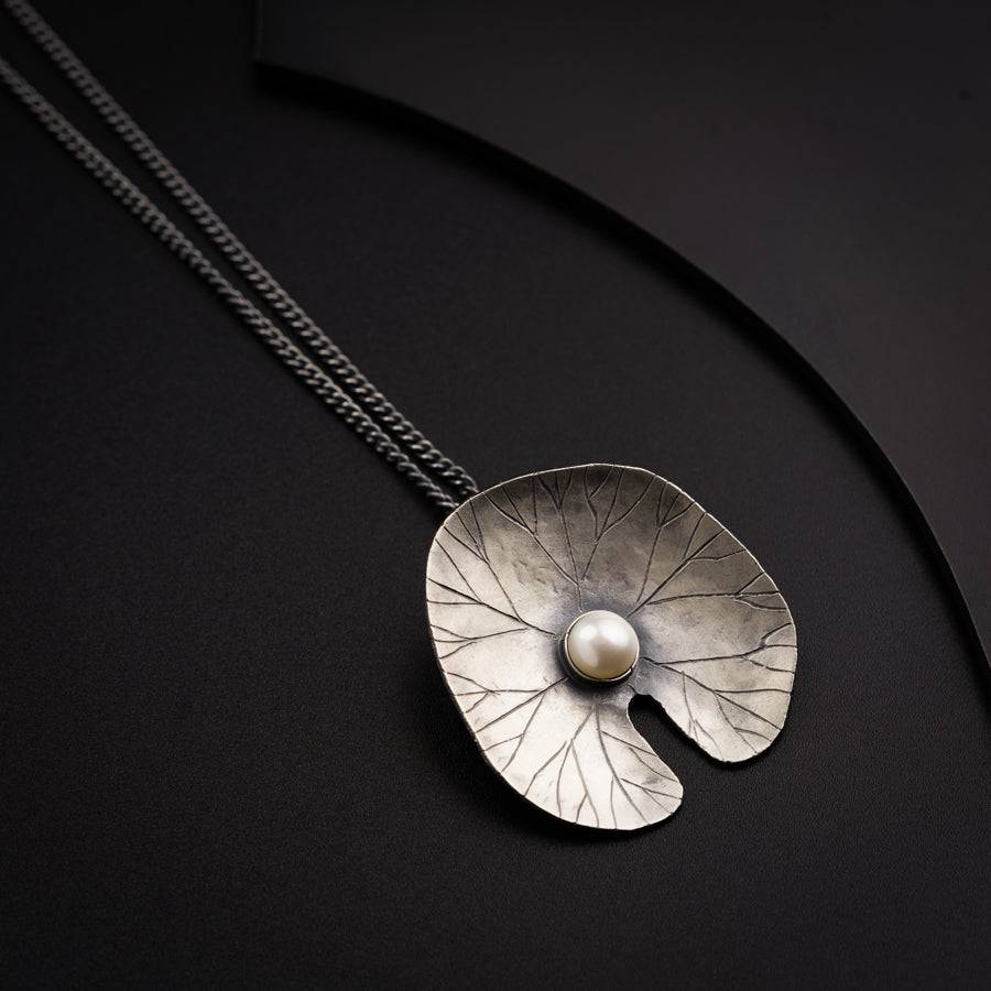 a silver pendant with a pearl hanging from it