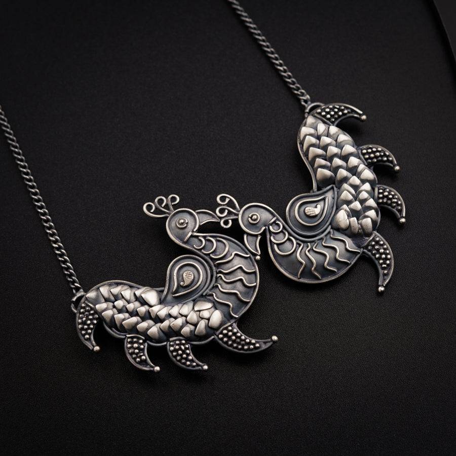 a silver necklace with two birds on it