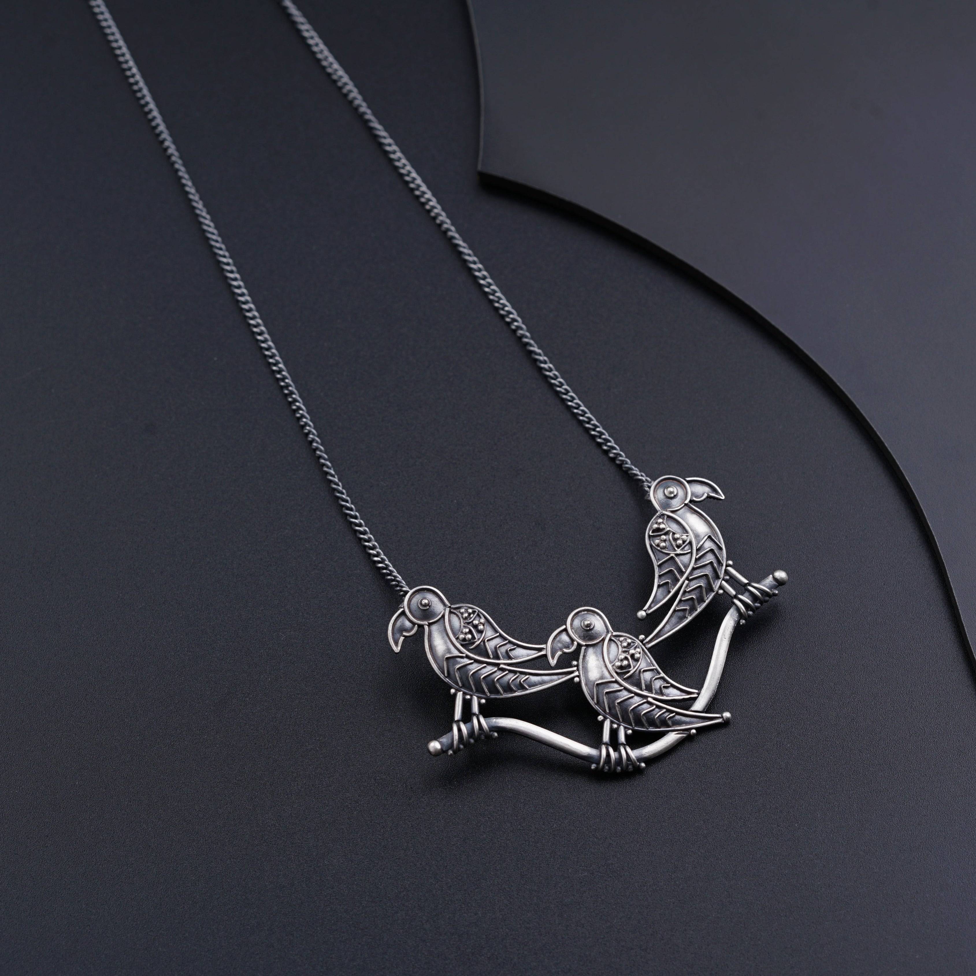 a couple of birds sitting on top of a necklace