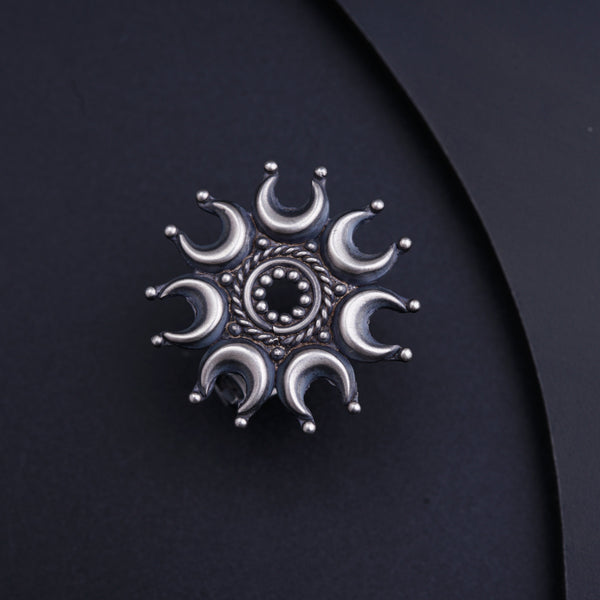 a silver brooch sitting on top of a black surface