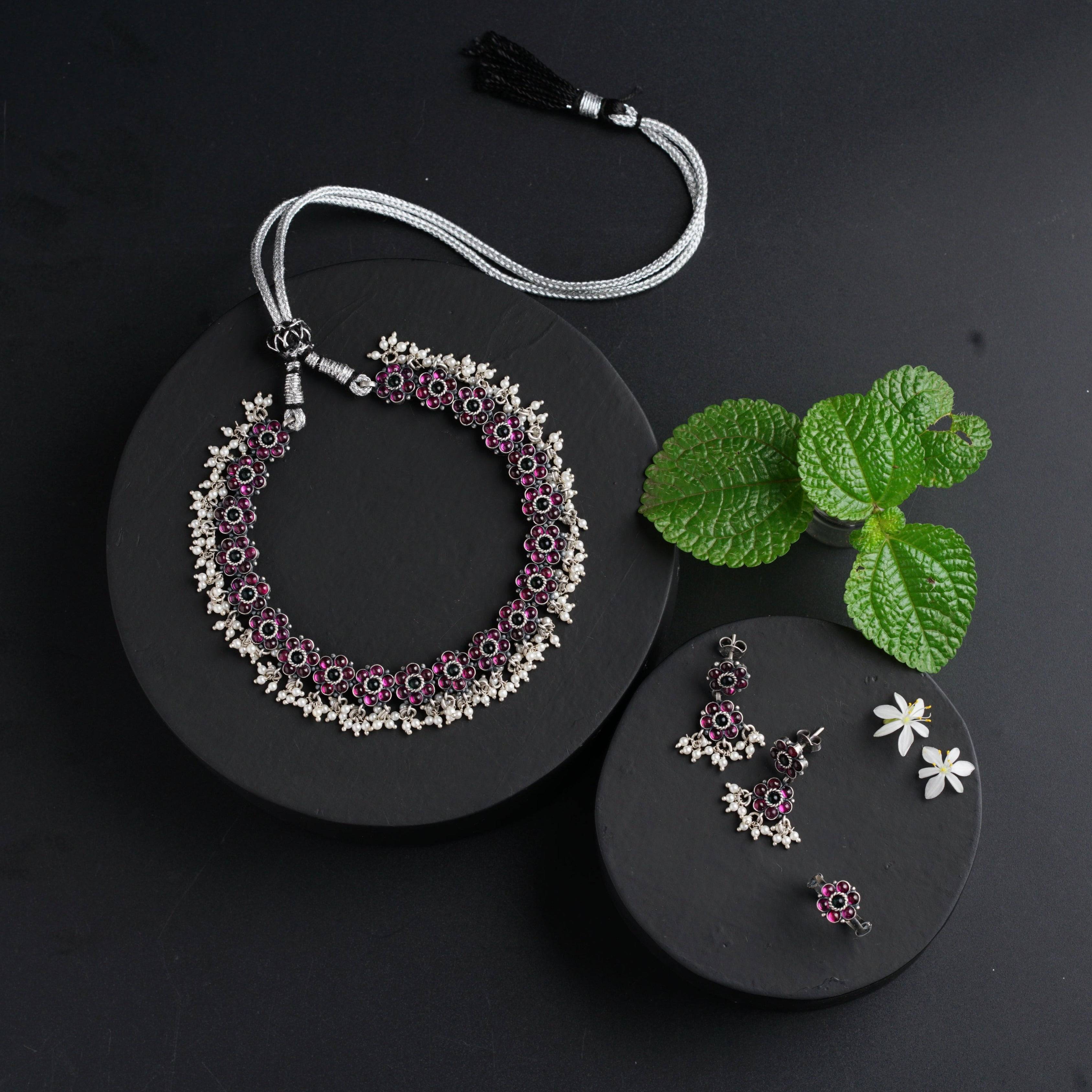a necklace and earrings on a plate next to a leaf