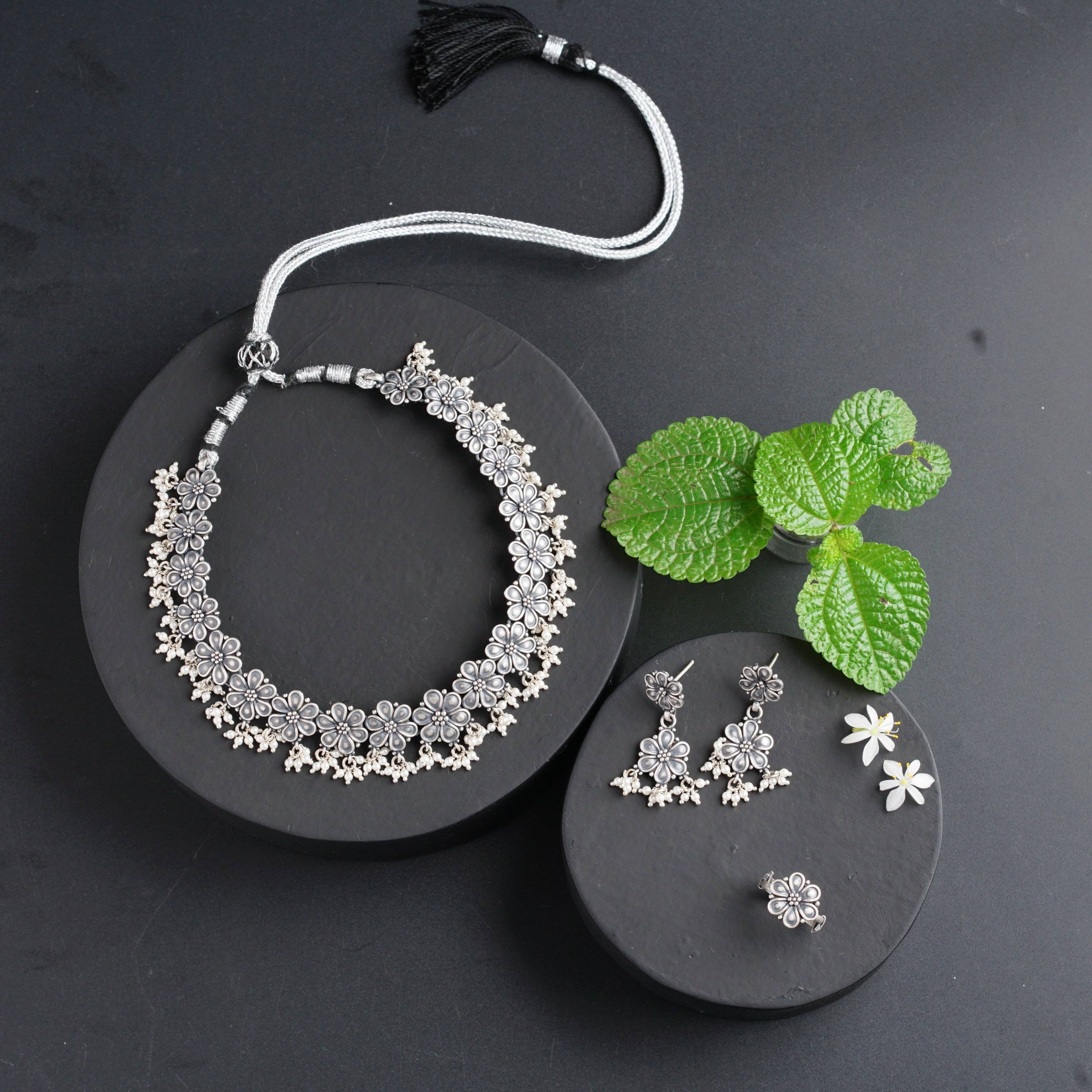 a necklace, earrings and a leaf on a black plate