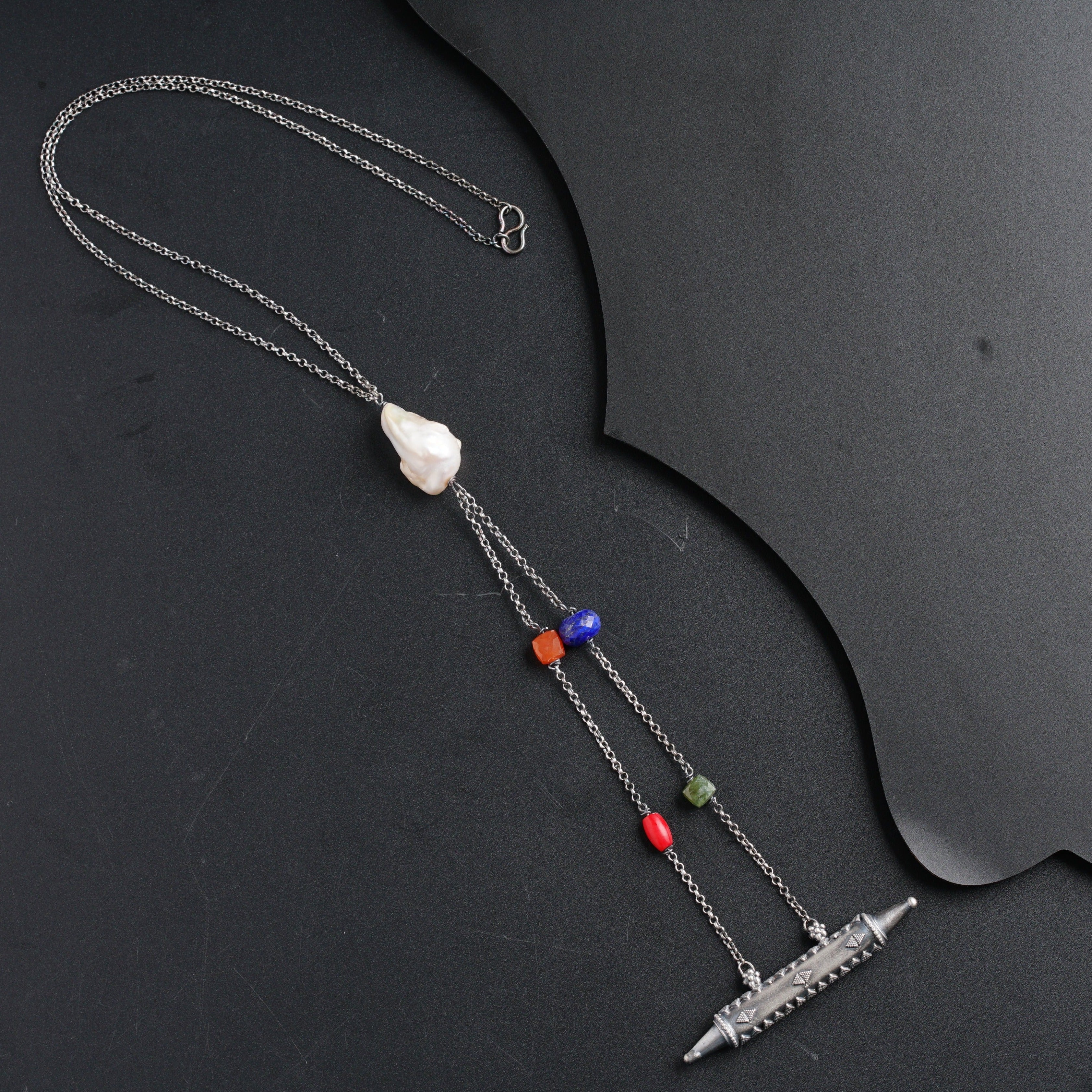 a necklace with a knife and beads on it