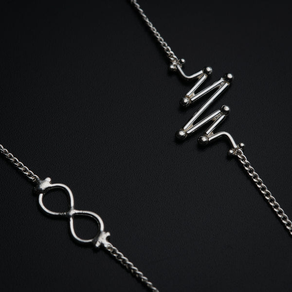 a couple of silver necklaces sitting on top of a table