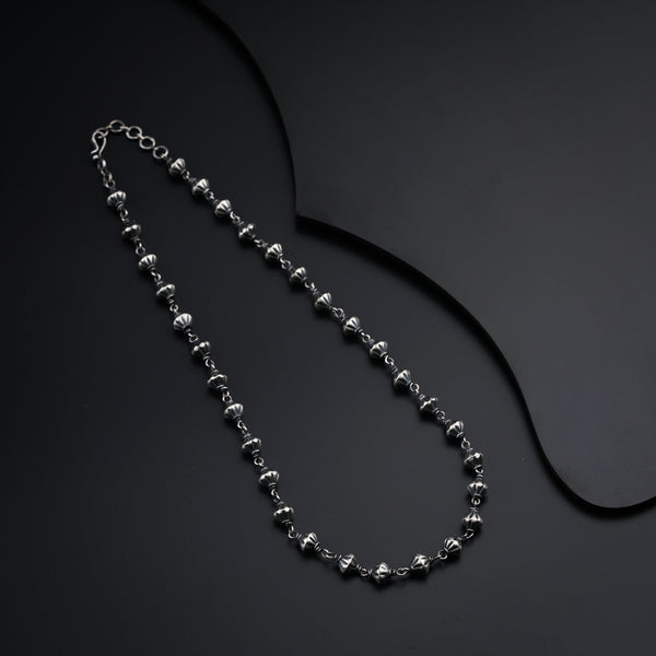 a silver beaded necklace on a black surface