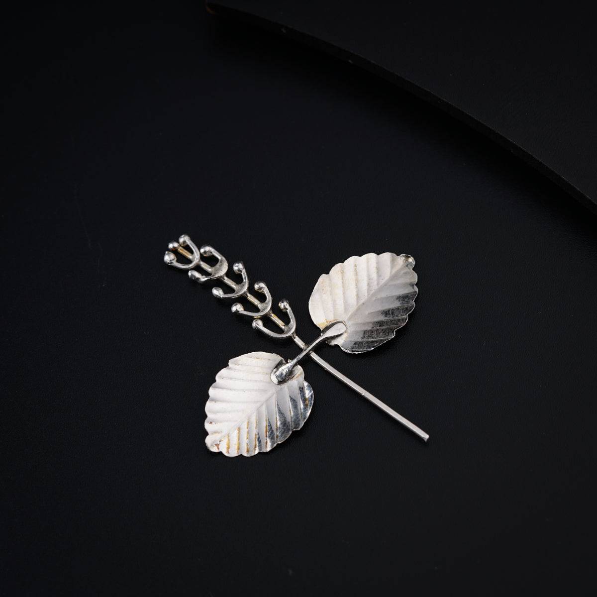 a white brooch with two leaves attached to it