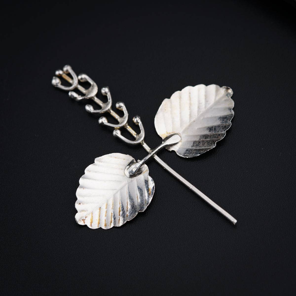 a silver brooch with a leaf on it