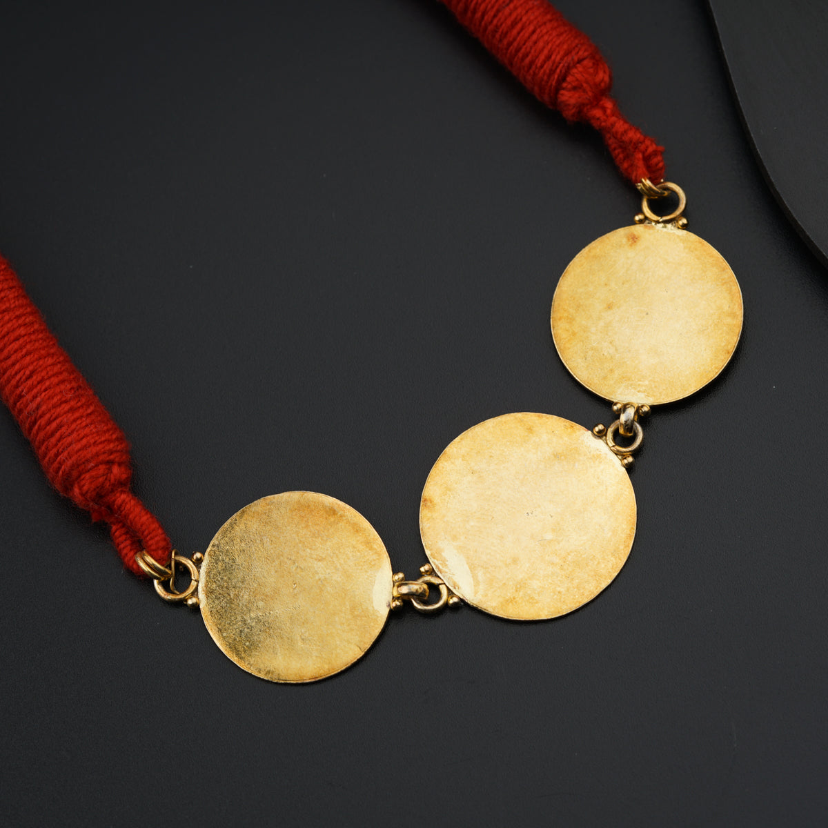 a necklace with three discs on a red string