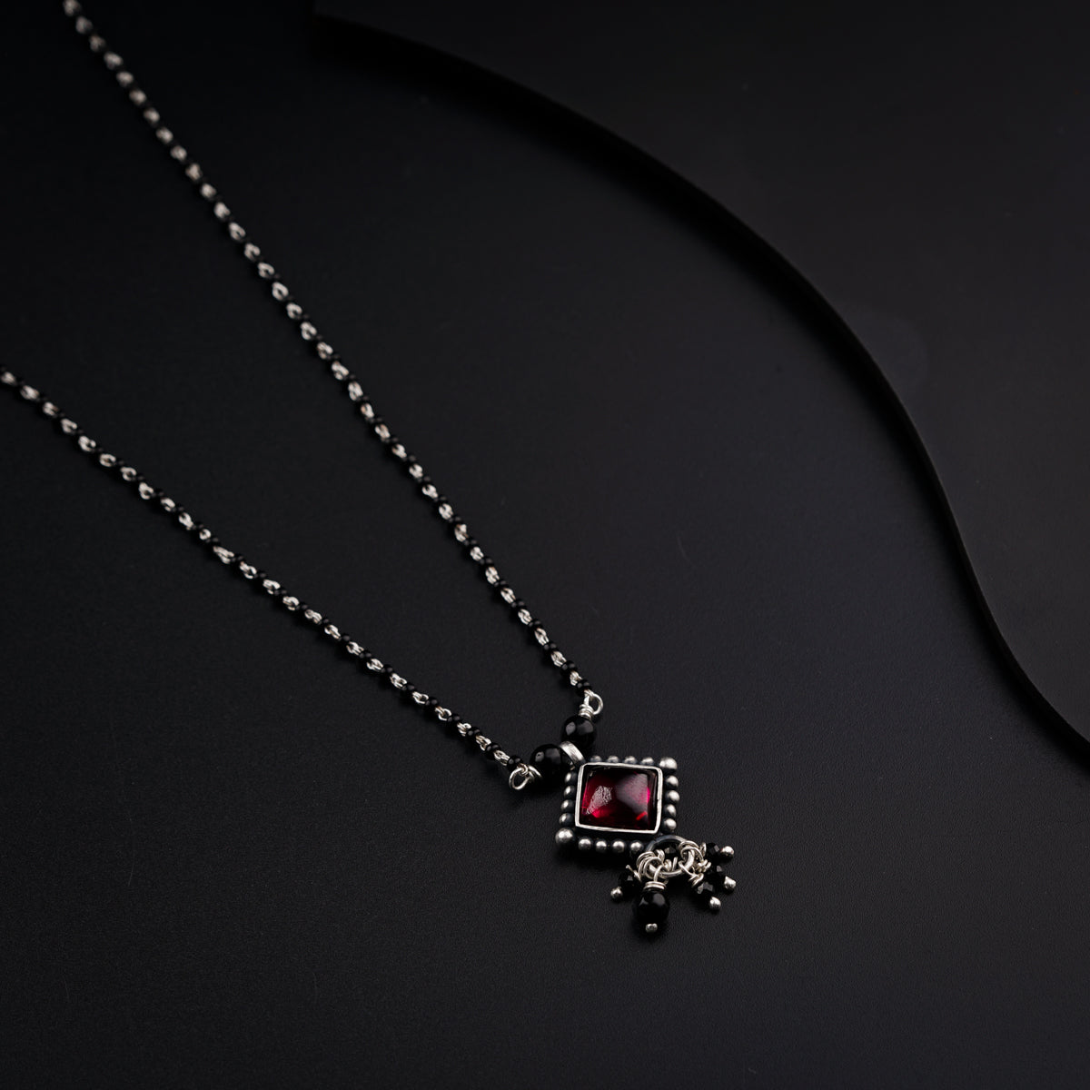 a necklace with a red stone and a cross on it