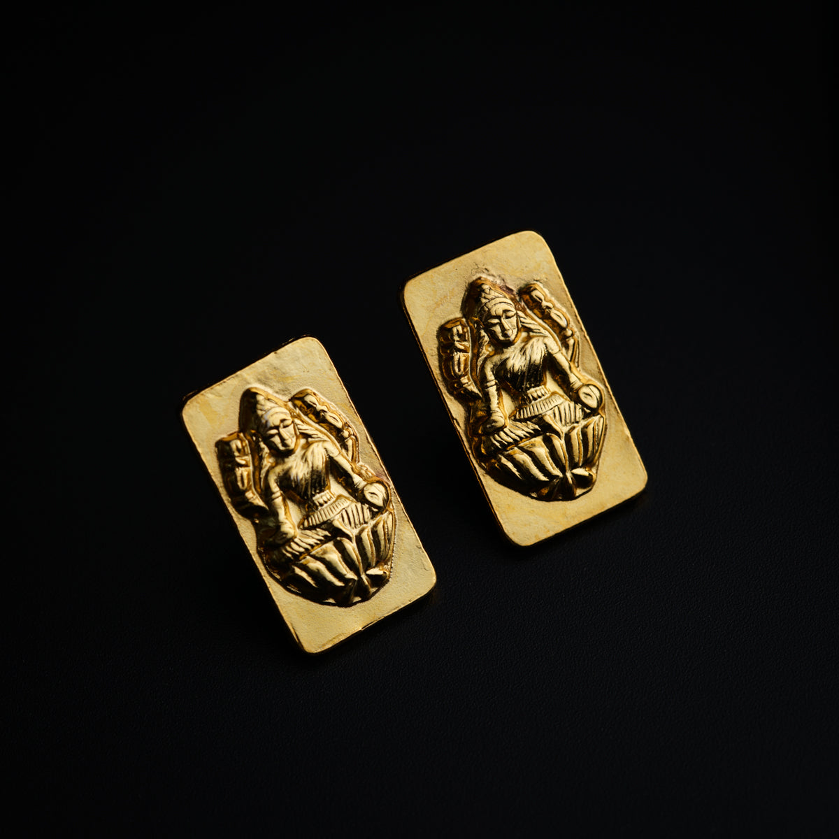 a pair of gold earrings with an image of a woman on it