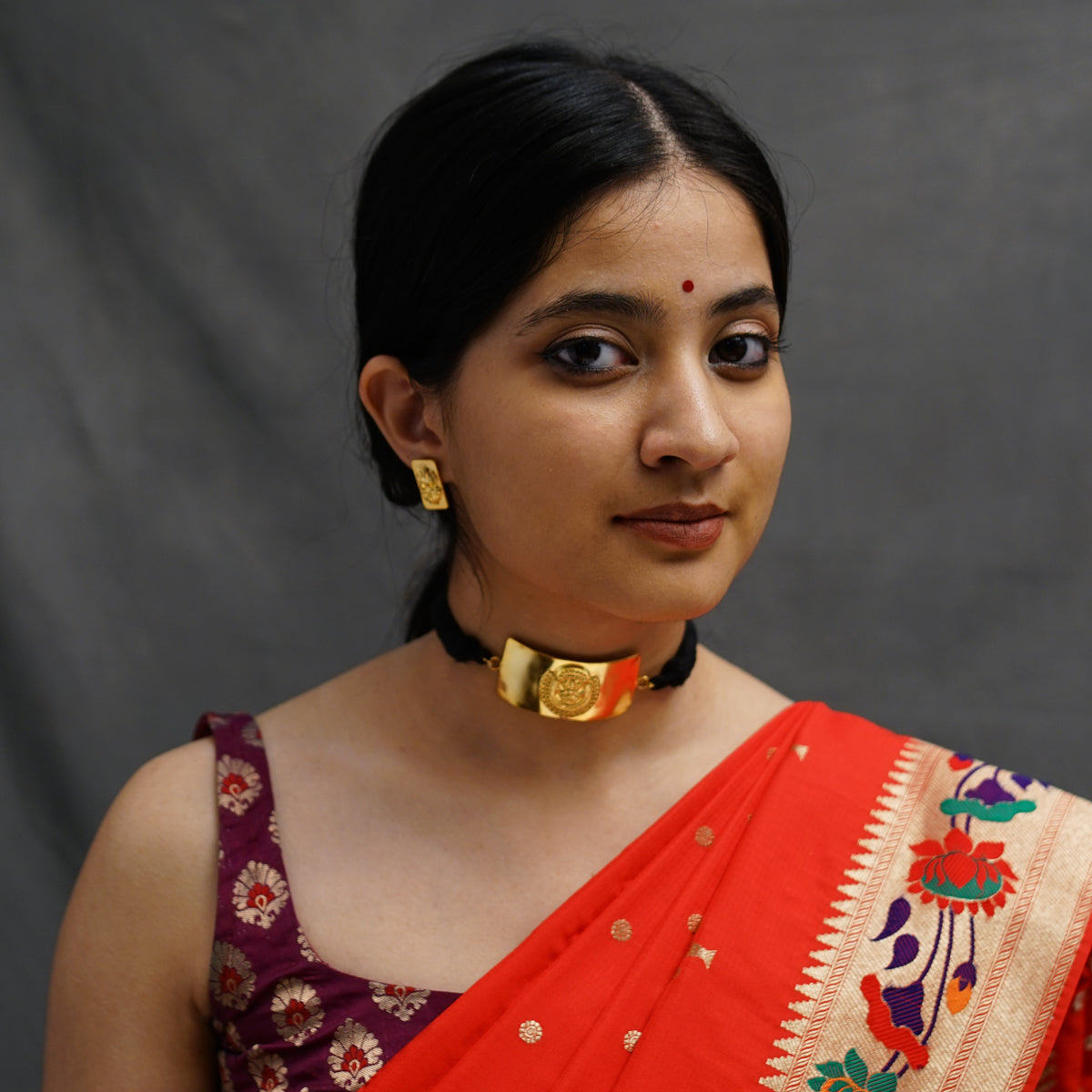 a woman wearing a red and gold sari
