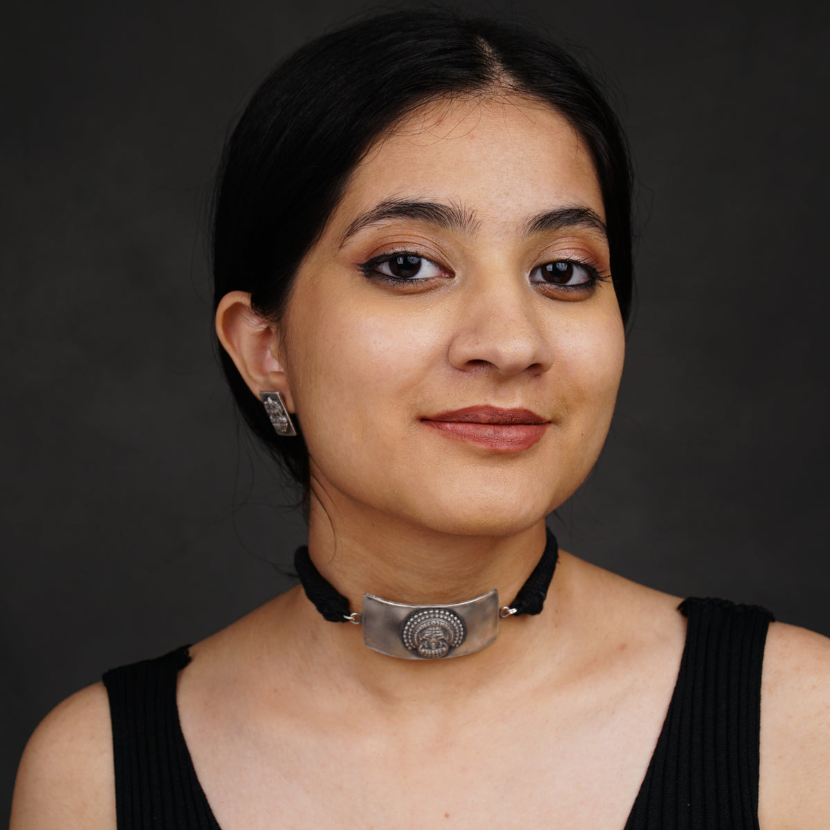 a woman wearing a black top and a silver choker