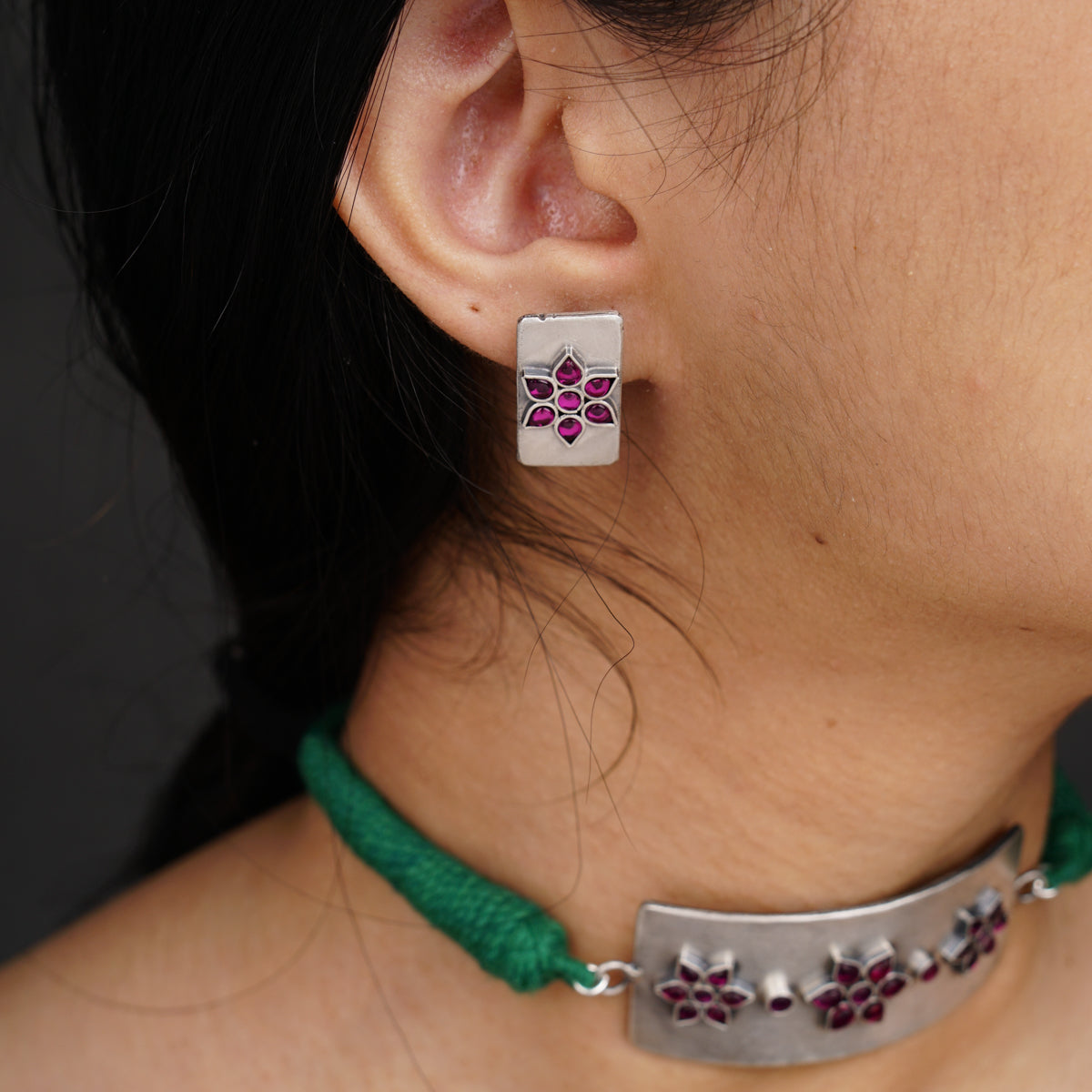 a close up of a person wearing a necklace and earrings