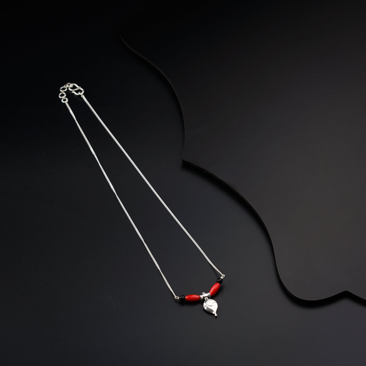 a pair of red and silver necklaces on a black background