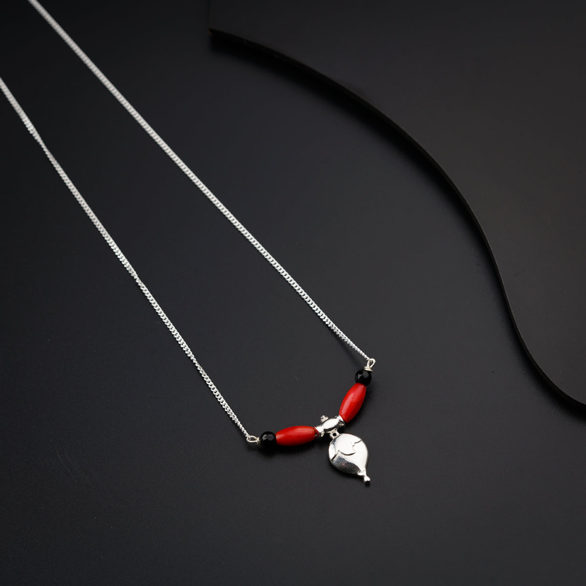a necklace with a red bead hanging from it