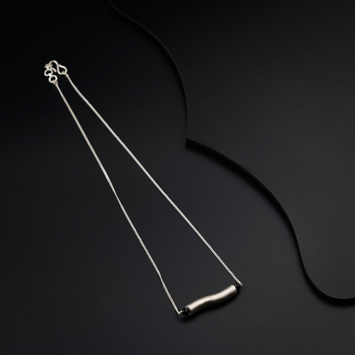 a pair of silver necklaces on a black surface