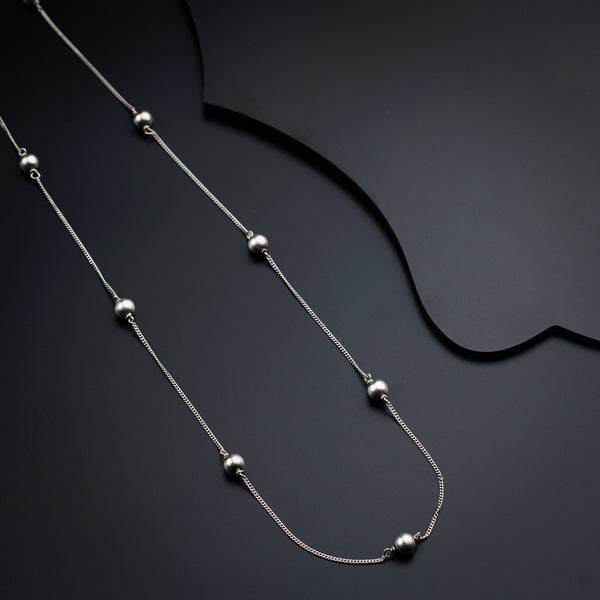 a silver necklace with balls on a black background