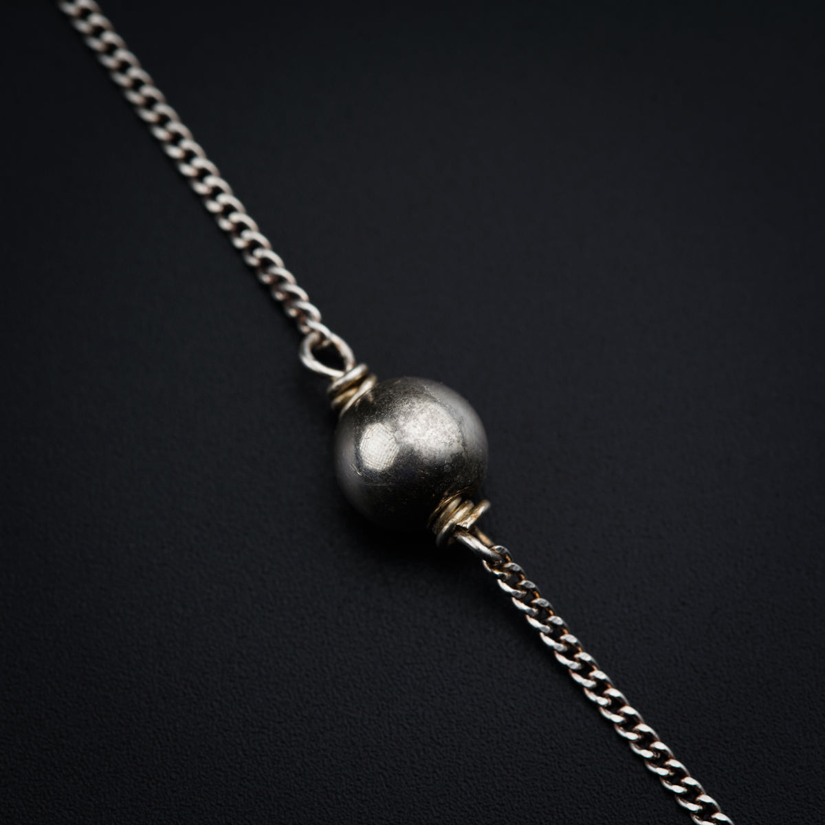 a silver ball on a chain on a black surface