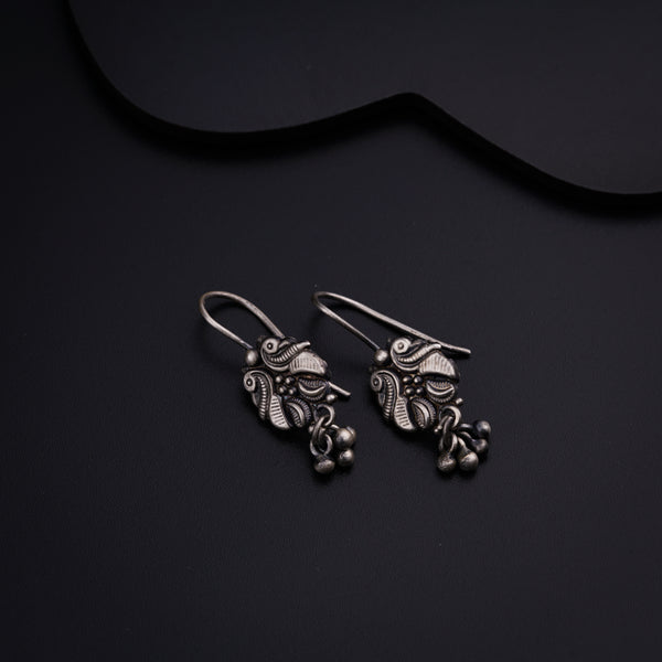 a pair of silver earrings sitting on top of a black surface