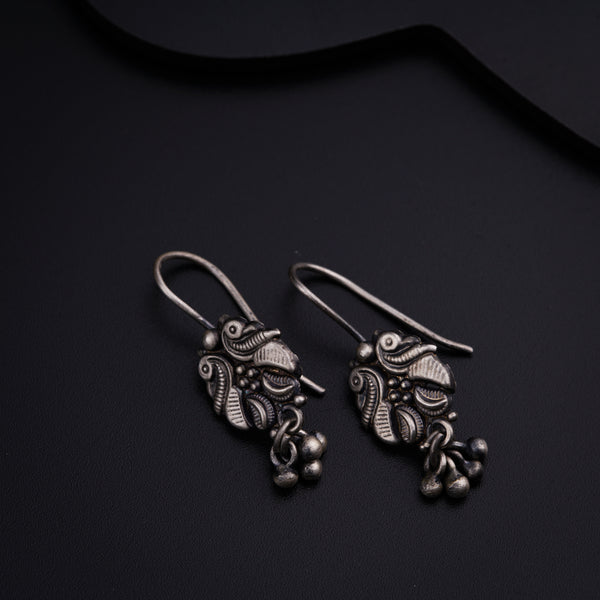 a pair of silver earrings on a black surface